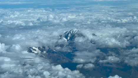 an elevated aerial view taken from a jet cockpit flying near the summit of the mont blanc, with few snow, in a summer morning, surroended by cottony clouds
