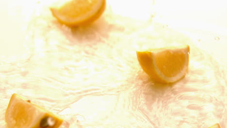 Pieces-of-lemon-falling-on-white-wet-surface