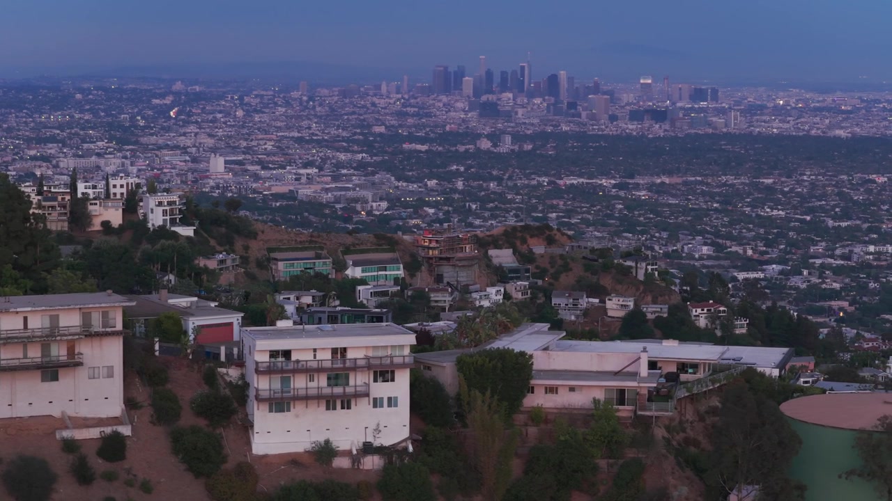 Ripresa aerea con dolly e teleobiettivo di case in collina che si affacciano su Los Angeles al crepuscolo nella California meridionale. 4K
