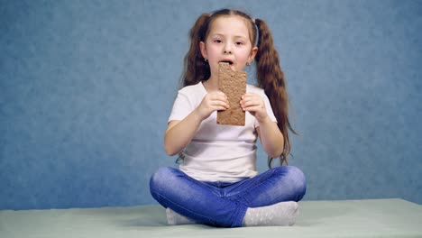 girl eating chocolate bar. girl sitting on the table and eating chocolate