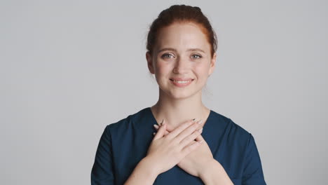 redheaded nurse in front of camera on gray background.