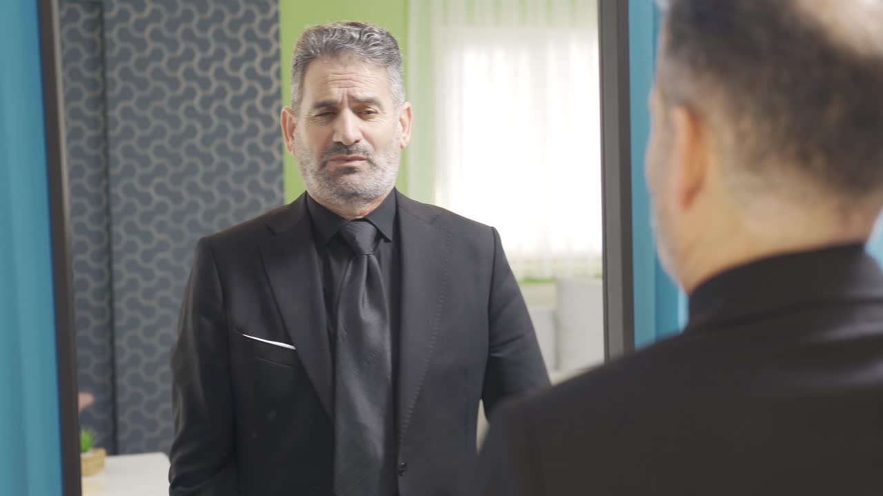 자신감 넘치는 성공적인 사업가가 거울 앞에서 자신에게 향수를 스프레이하고 있습니다.