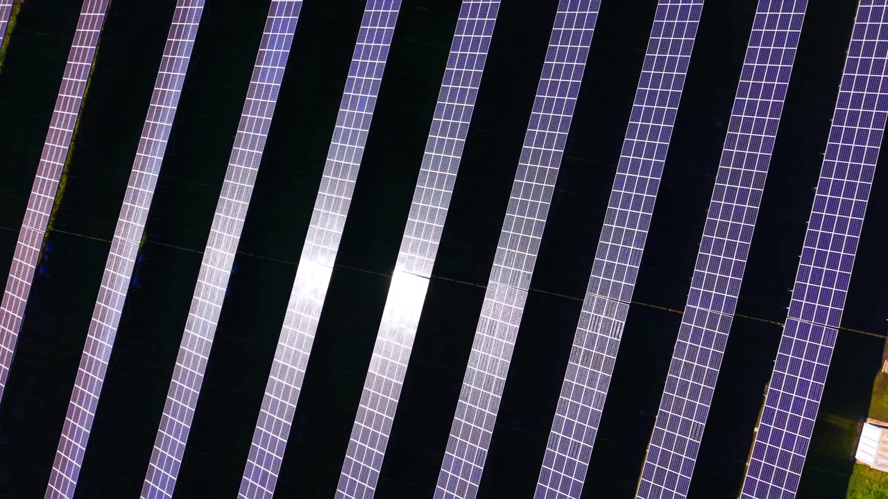 Composizione a schema dall'alto di moduli elettrici su terreno scuro con raggi solari luminosi che colpiscono la superficie. Vista diagonale di file di un impianto solare sostenibile dall'alto