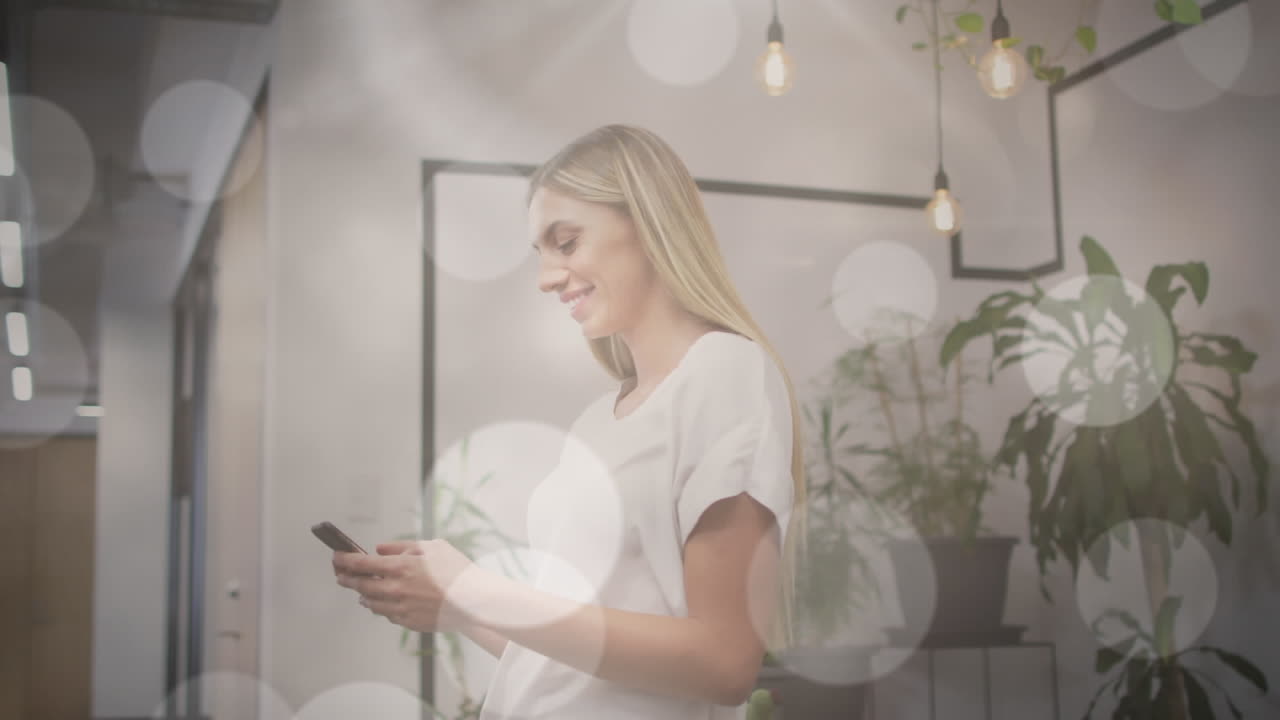 사무실에서 스마트폰을 사용하는 행복한 백인 여성 위에 보케 빛 반점의 애니메이션