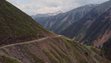 vista aérea de un dron moviéndose hacia adelante sobre un alto paso de montaña cerca de peer ki gali en cachemira con montañas cubiertas de nieve en el fondo