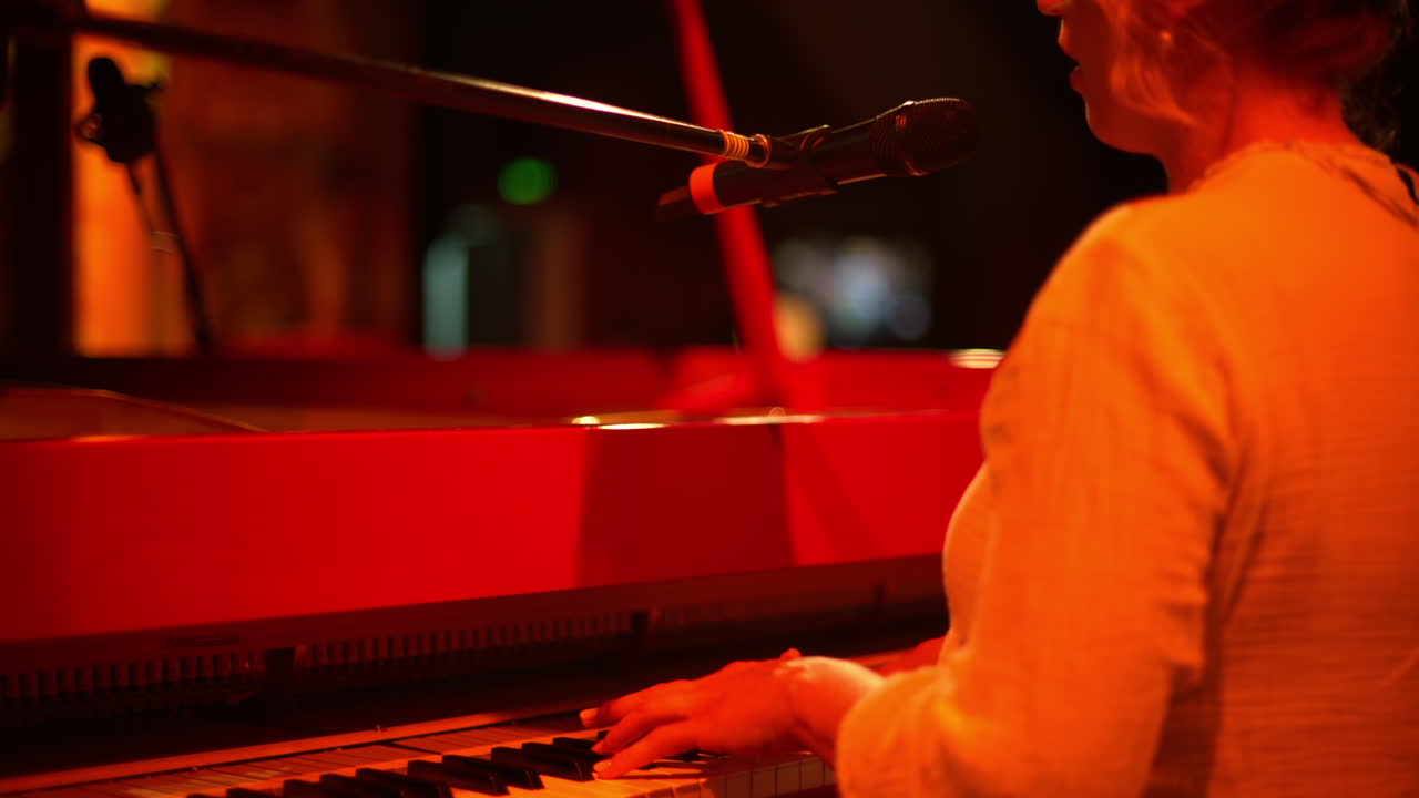 Woman singing into the microphone and playing a red piano