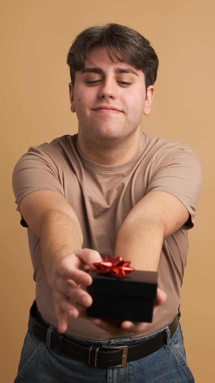 Happy man giving present and looking at camera