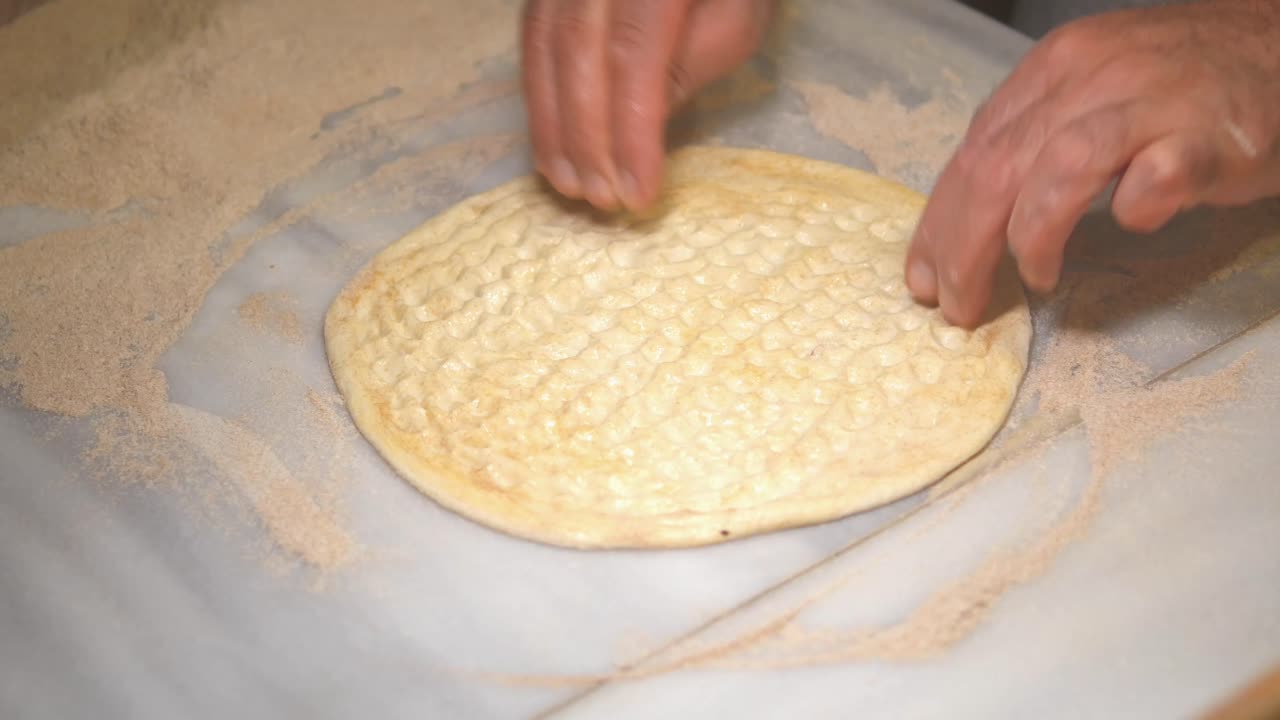 Hands preparing and shaping dough on a floured surface
