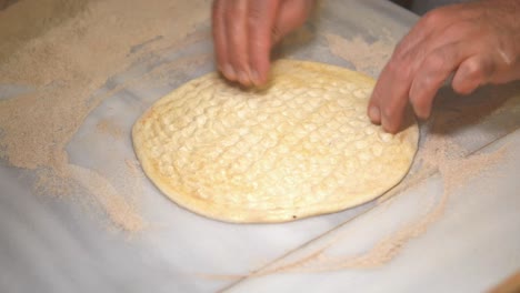 hands preparing and shaping dough on a floured surface