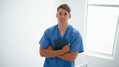 retrato de un médico o enfermera de sexo masculino con una tableta digital de pie en las escaleras de un hospital