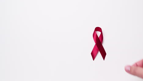 detail of male hand putting ribbon in red color on white background