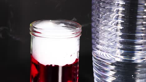 A vibrant chemical reaction produces fuming smoke in a glass jar, creating a dynamic visual effect