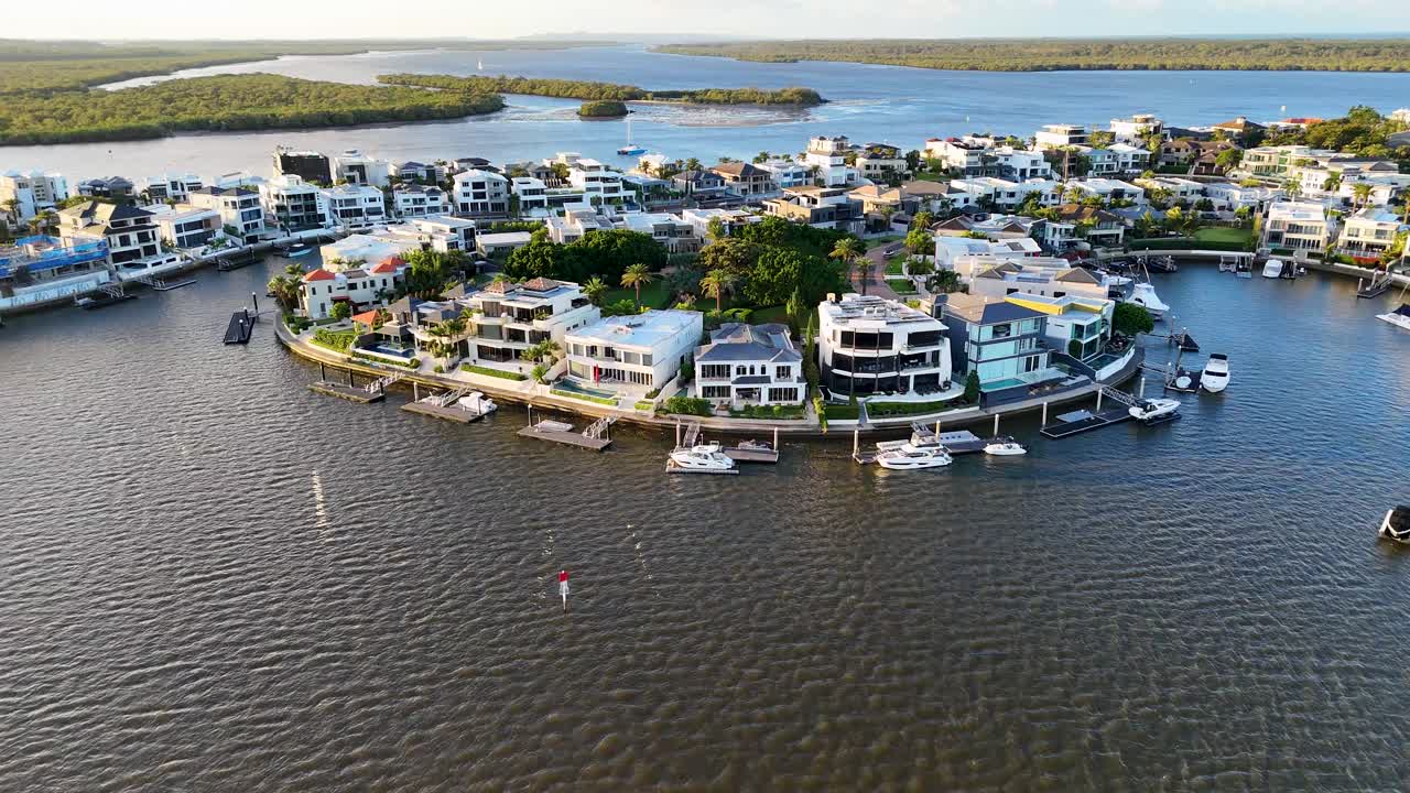 Drone footage captures luxury estates and boats along Gold Coast's waterfront under bright daylight, showcasing serene coastal living