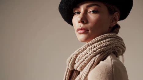 close-up of a woman in a beige knitted scarf and black hat