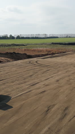 vast earthwork site with construction equipment and distant rural landscape