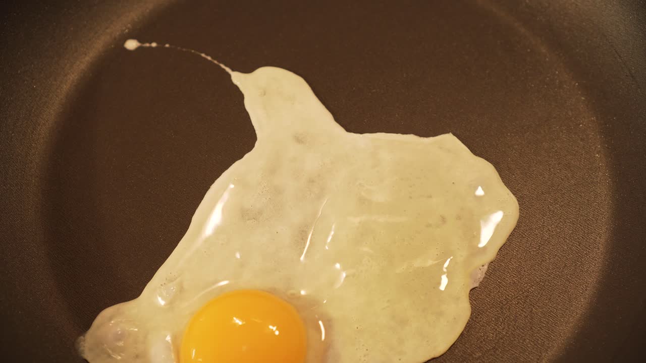 Pouring egg into teflon pan and frying it - closeup