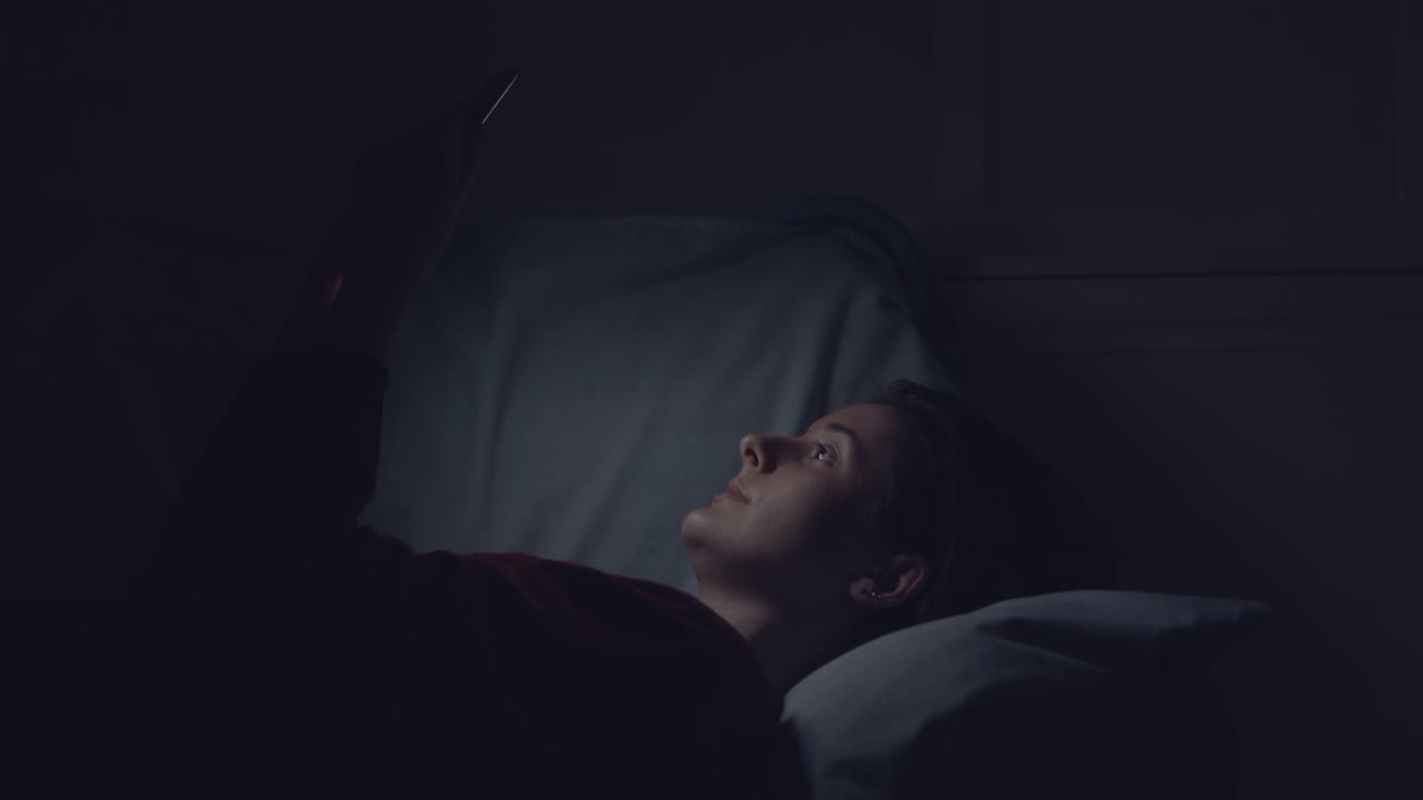 mujer usando el teléfono en la cama por la noche