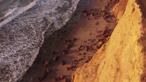 vista aérea de arriba hacia abajo de la playa sobre el borde del acantilado durante la puesta de sol