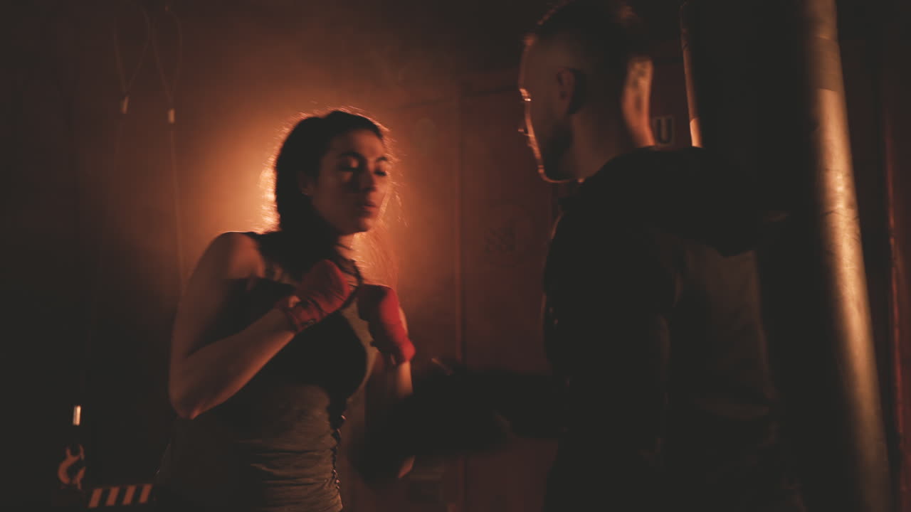 여자 복서가 트레이너의 장갑을 끼고 스트라이크를 피하다 2