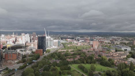 aerial view flying across deansgate square parkland and skyscrapers on overcast manchester city landscape