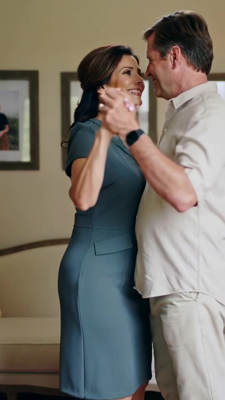 Video verticale: Coppia danzante che segue il passo dell'uomo, ondeggiando a casa, condividendo un momento romantico vicino al divano.
