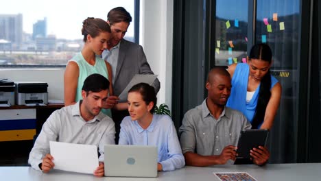 Business-executives-discussing-over-laptop-and-digital-tablet