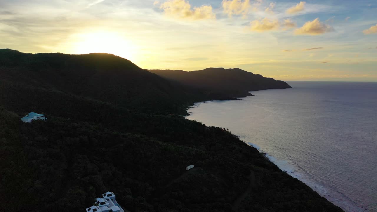 Vibrant, colorful skies reflect gently on the smooth ocean waters of St. Croix, USVI, where a forested island point stands silhouetted against the peaceful, glowing horizon