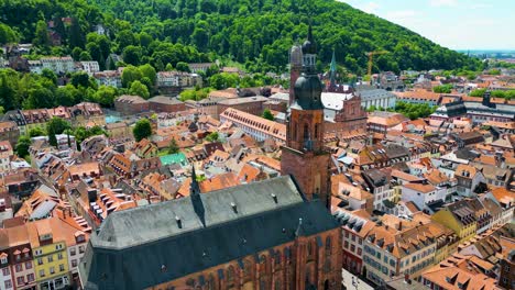 4k aerial drone video of the beautiful heiliggeistkirche and jesuitenkirche churches along the neckar river in heidelberg, germany