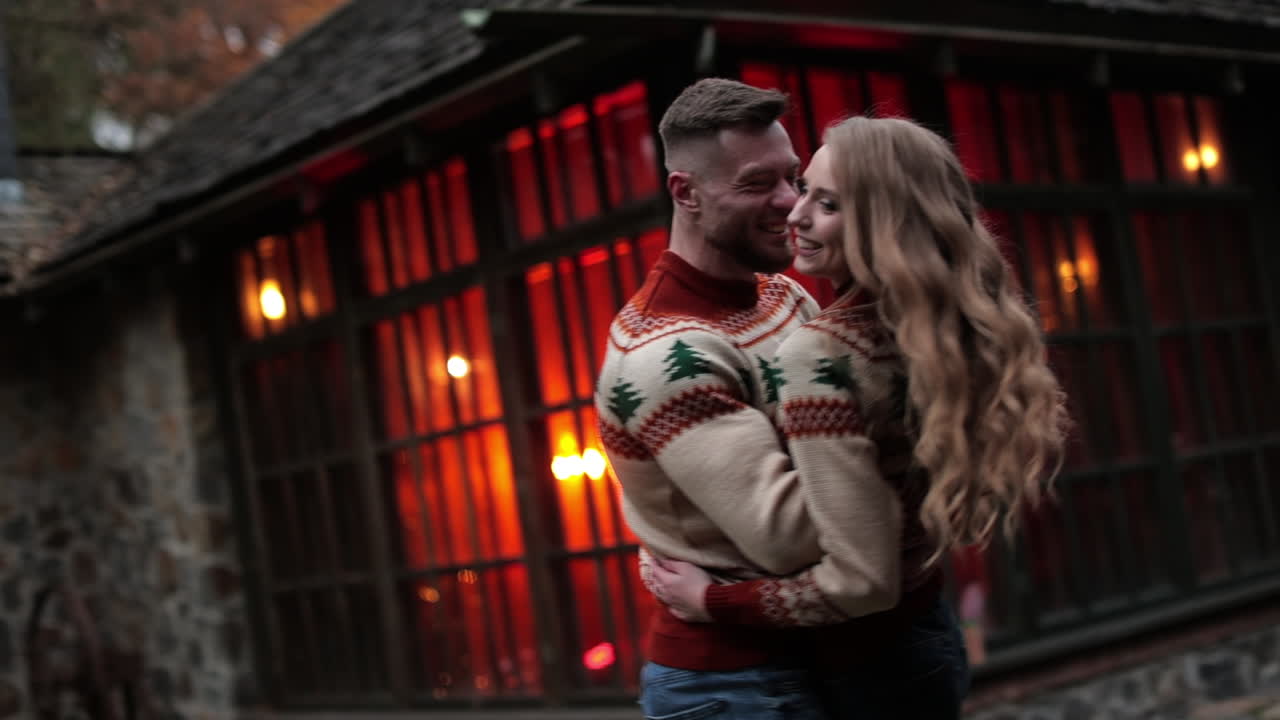 Joyful couple having date outside the city. Happy couple dancing, hugging and laughing at the rural manor. Man and woman having fun at the backdrop of beautiful old wooden house.