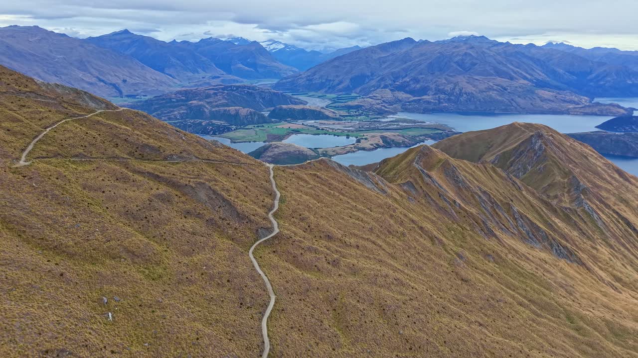 Drone footage flying high above the Roys Peak hiking trail in Wanaka, New Zealand, revealing the lake and surrounding mountains