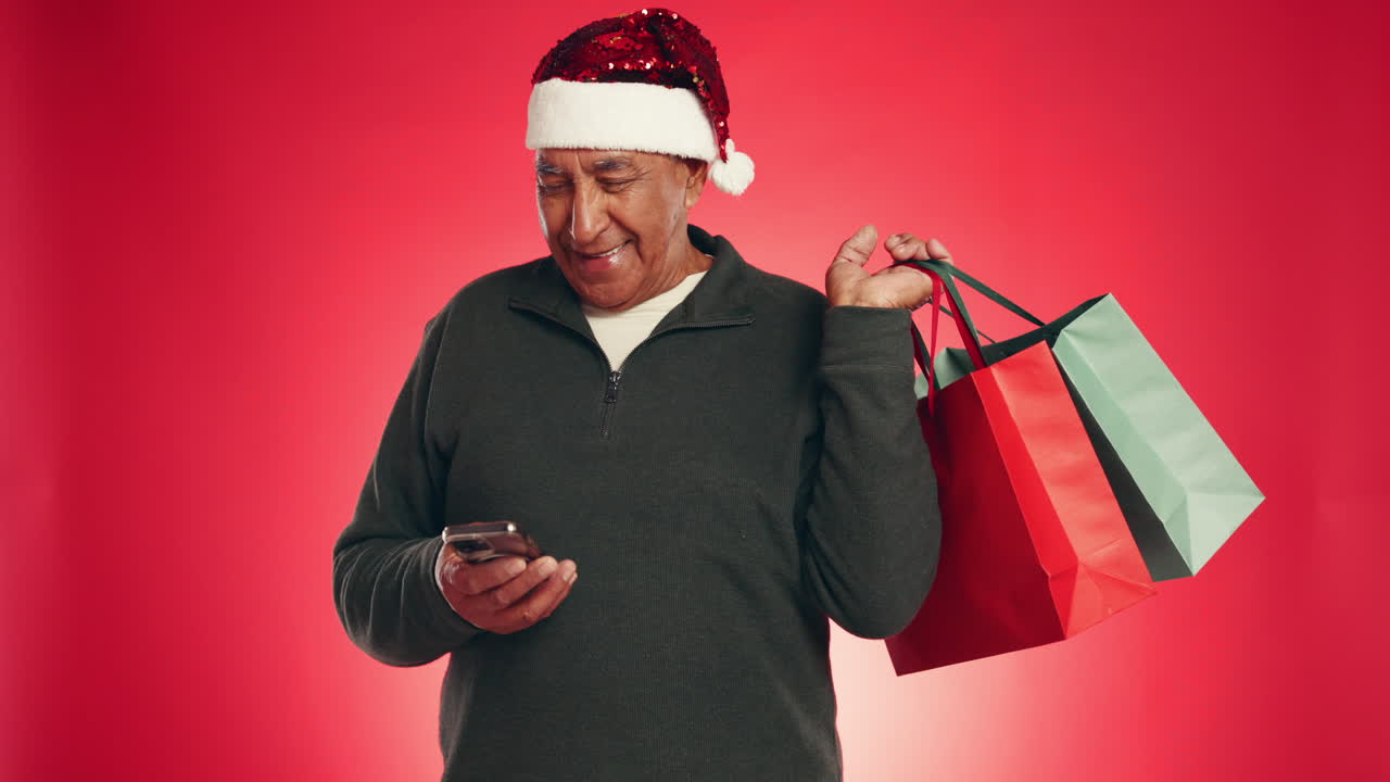 Man in Santa hat using phone with shopping bags