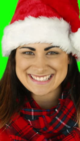 una morena festiva con el sombrero de papá noel soplando sobre las manos.