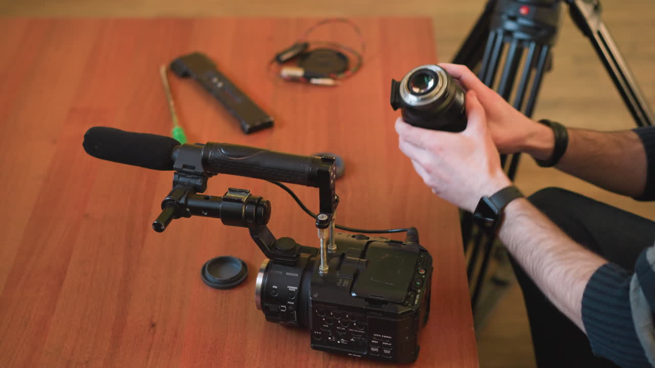 close-up of hands fixing camera, microphone setup on tripod, preparing equipment for video production. preparing gear for professional filming, mounting camera and microphone for shooting