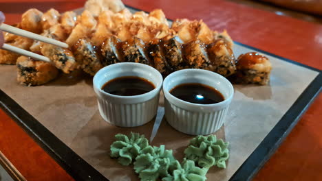 various type of sushi on plate, chopsticks pick attempt to avoid hungriness, dish ready along soy sauce and wasabi