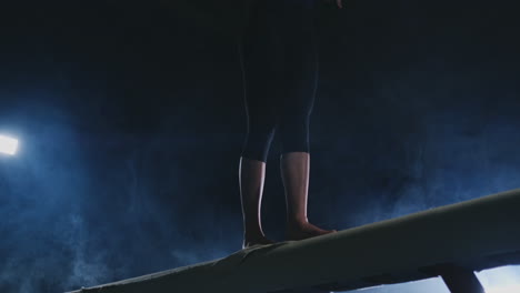 girl gymnast practicing on a balance beam in gym.