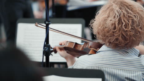 un violinista en la parte de atrás toca música clásica en una orquesta