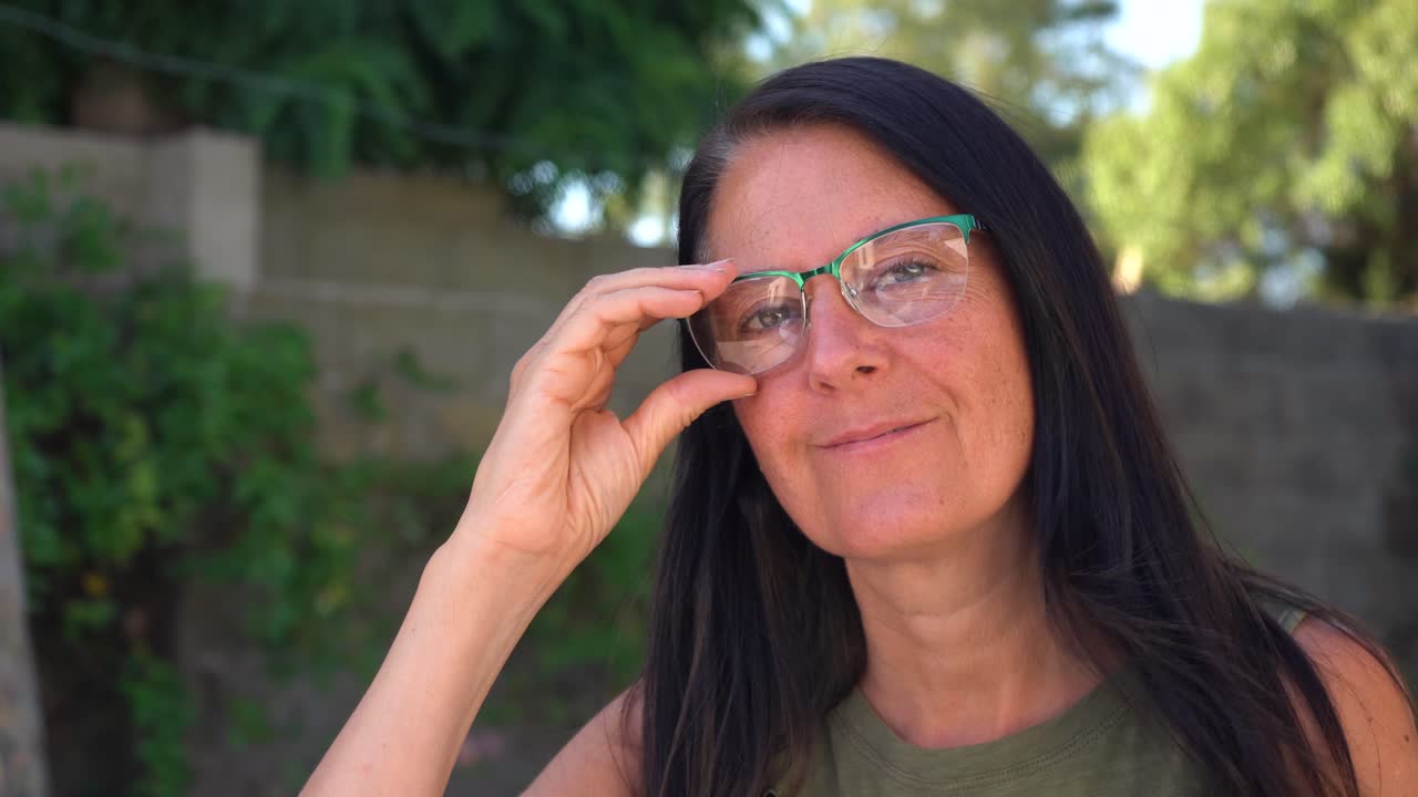 primer plano de mujer de mediana edad con gafas leyendo y mirando a la cámara