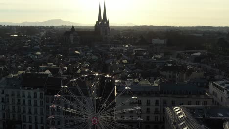 Gran-Rueda-De-La-Fortuna-En-La-Ciudad-De-Bayona-Con-La-Catedral-De-Fondo-Al-Atardecer,-Francia