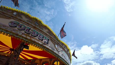 traditional carousel with union jack flags waving under blue sky in liverpool