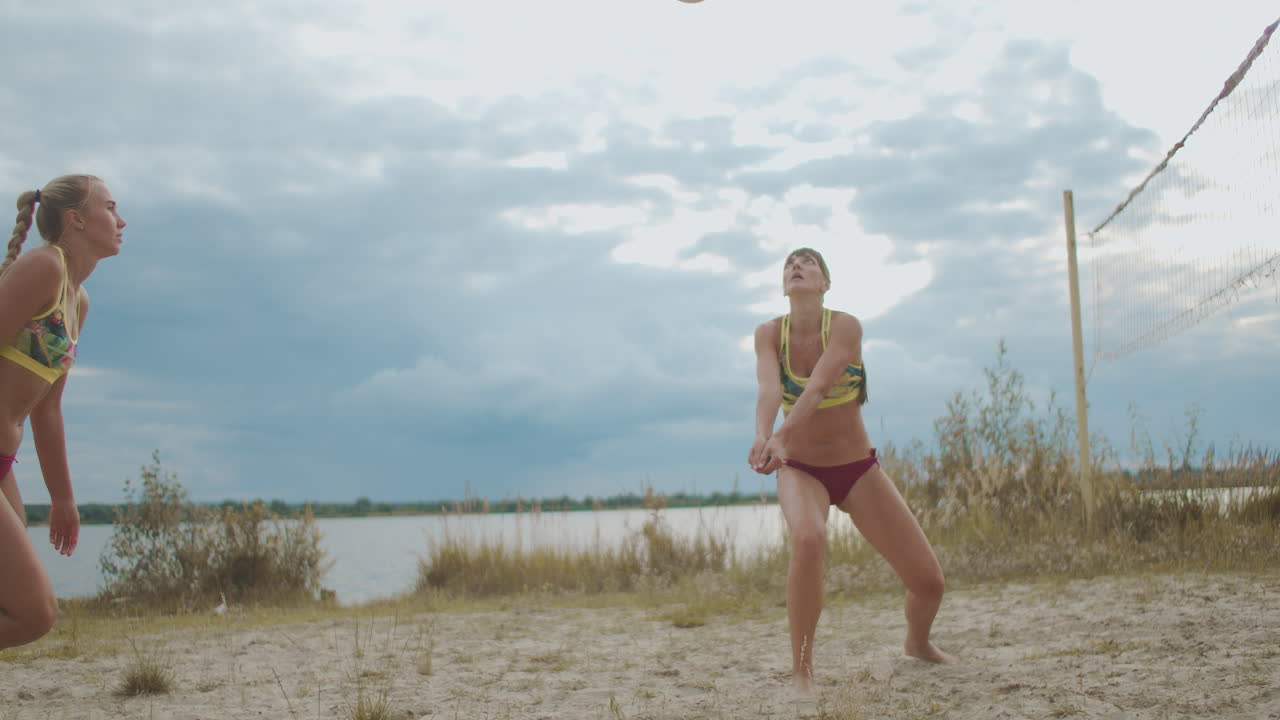 спортивные женщины играют в пляжный волейбол на песчаном корте летом. команда из двух игроков. атлетические дамы прыгают.