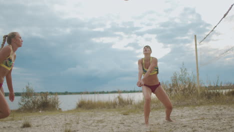 mujeres deportivas están jugando voleibol de playa en la cancha de arena en verano dos jugadores del equipo atlético mujeres están saltando