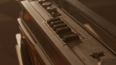 hand inserting audio cassette and pressing play button on vintage boombox