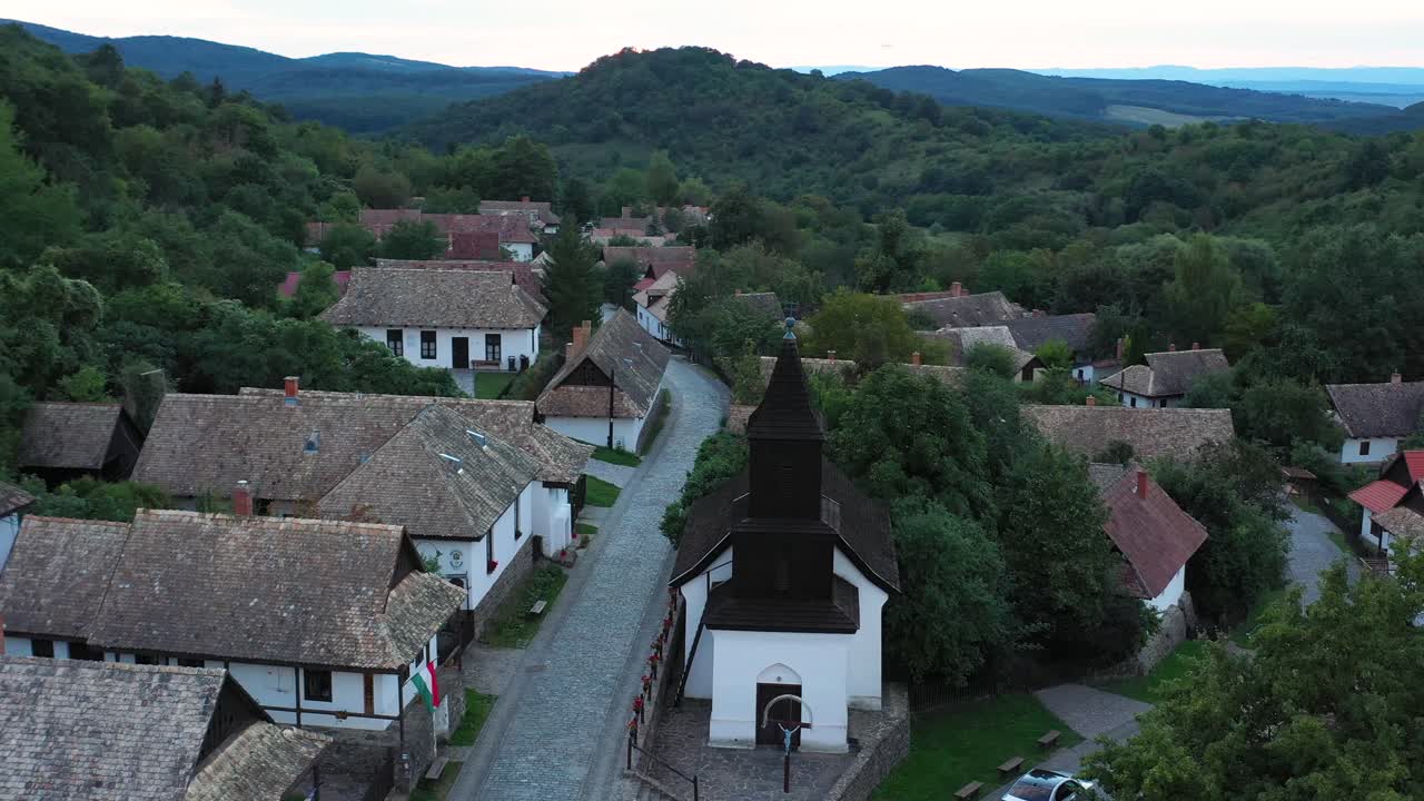 Dron przelatuje nad historycznymi ulicami Hollókő na Węgrzech o zachodzie słońca
