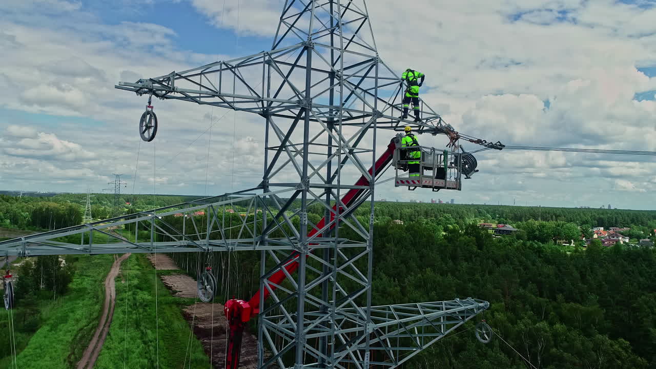 toma de drones en paralelo de técnicos en grúas elevadoras que trabajan en torres de electricidad de alto voltaje en su uniforme
