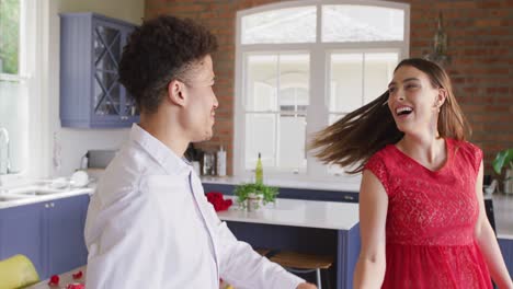feliz pareja biracial celebrando el día de san valentín bailando juntos en casa
