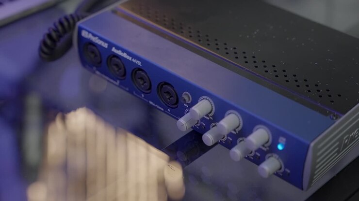 Audio capturing equipment is shown while hand wearing bracelet comes into frame to turn the equipment on