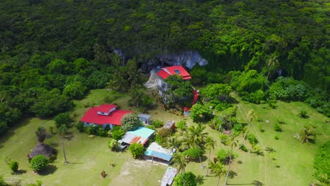 Captured-by-a-drone,-a-house-perched-on-a-rocky-coastal-outcropping-on-the-island-of-Lifou-comes-into-view