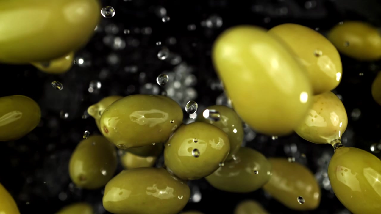 Olive verdi fresche con gocce d'acqua che cadono al rallentatore.