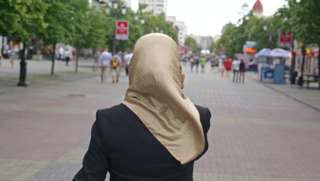 mujer de oriente medio contestando el teléfono en la calle de la ciudad