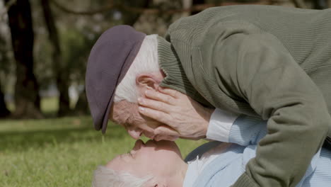 Una-Pareja-Romántica-De-Ancianos-Tirada-En-La-Hierba-Y-Besándose-Mientras-Pasa-Tiempo-En-El-Parque-El-Soleado-Día-De-Otoño